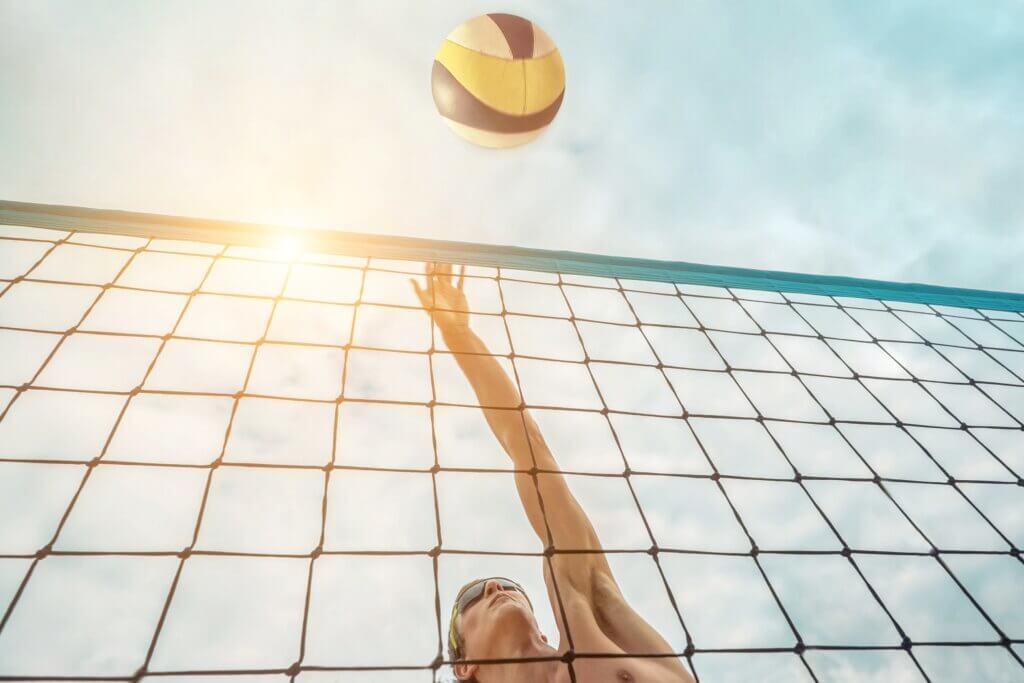 Beachvolleyballspieler schlägt Ball über das Netz