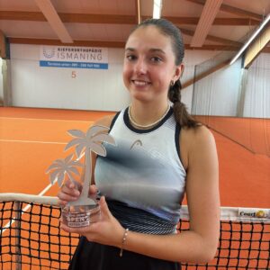 Tennisspielerin hält Pokal auf Hallenplatz