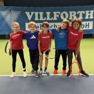 Kinder spielen Tennis in einer Sporthalle