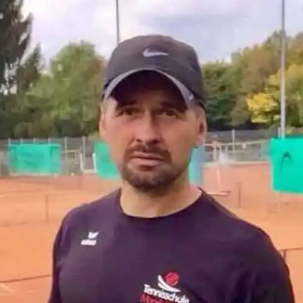 Tennistrainer steht auf einem Sandplatz