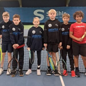 Kinder stehen mit Tennisschlägern auf dem Tennisplatz