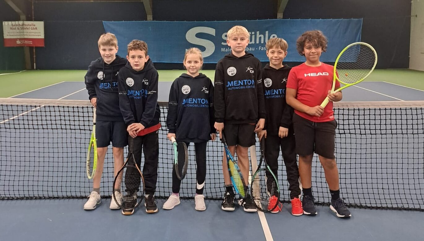 Kinder stehen mit Tennisschlägern auf dem Tennisplatz