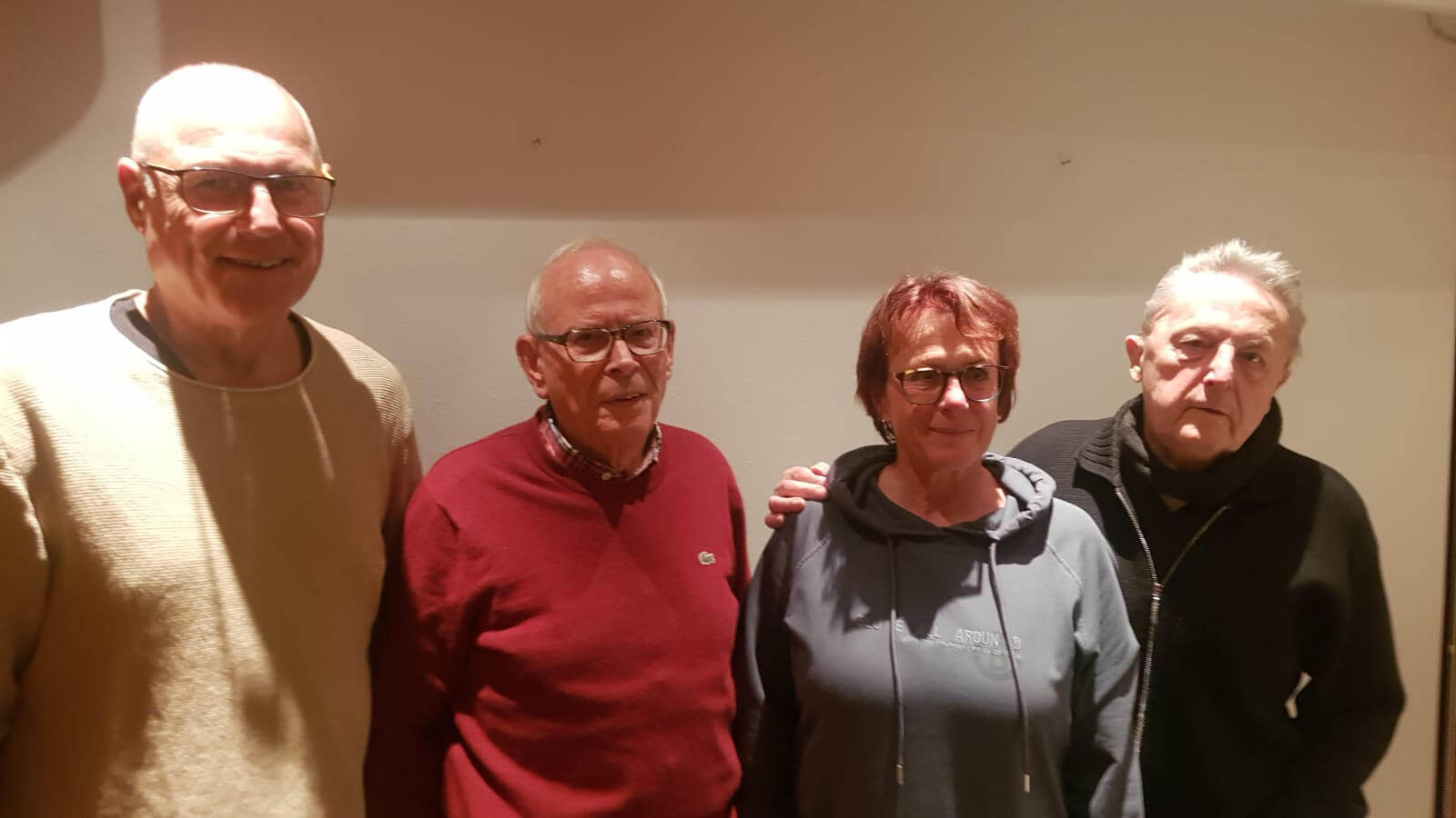 Vier ältere Personen stehen zusammen und lächeln