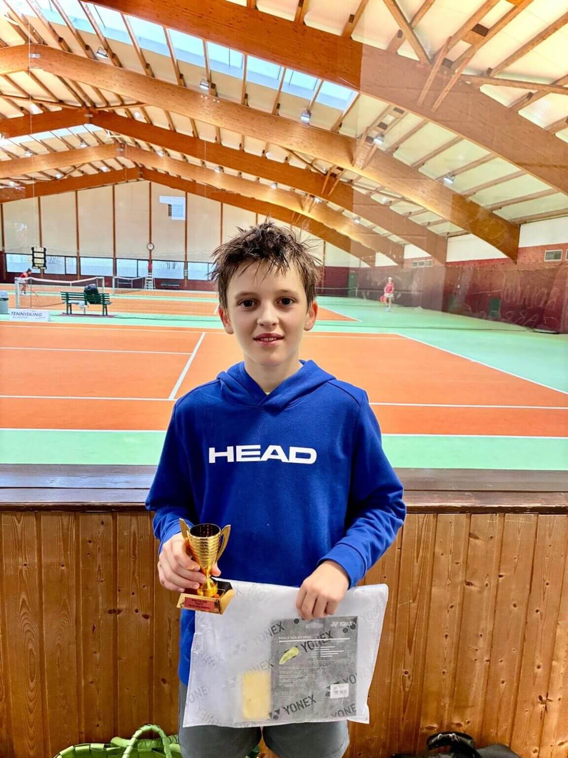 Junge hält Tennis-Pokal in Halle