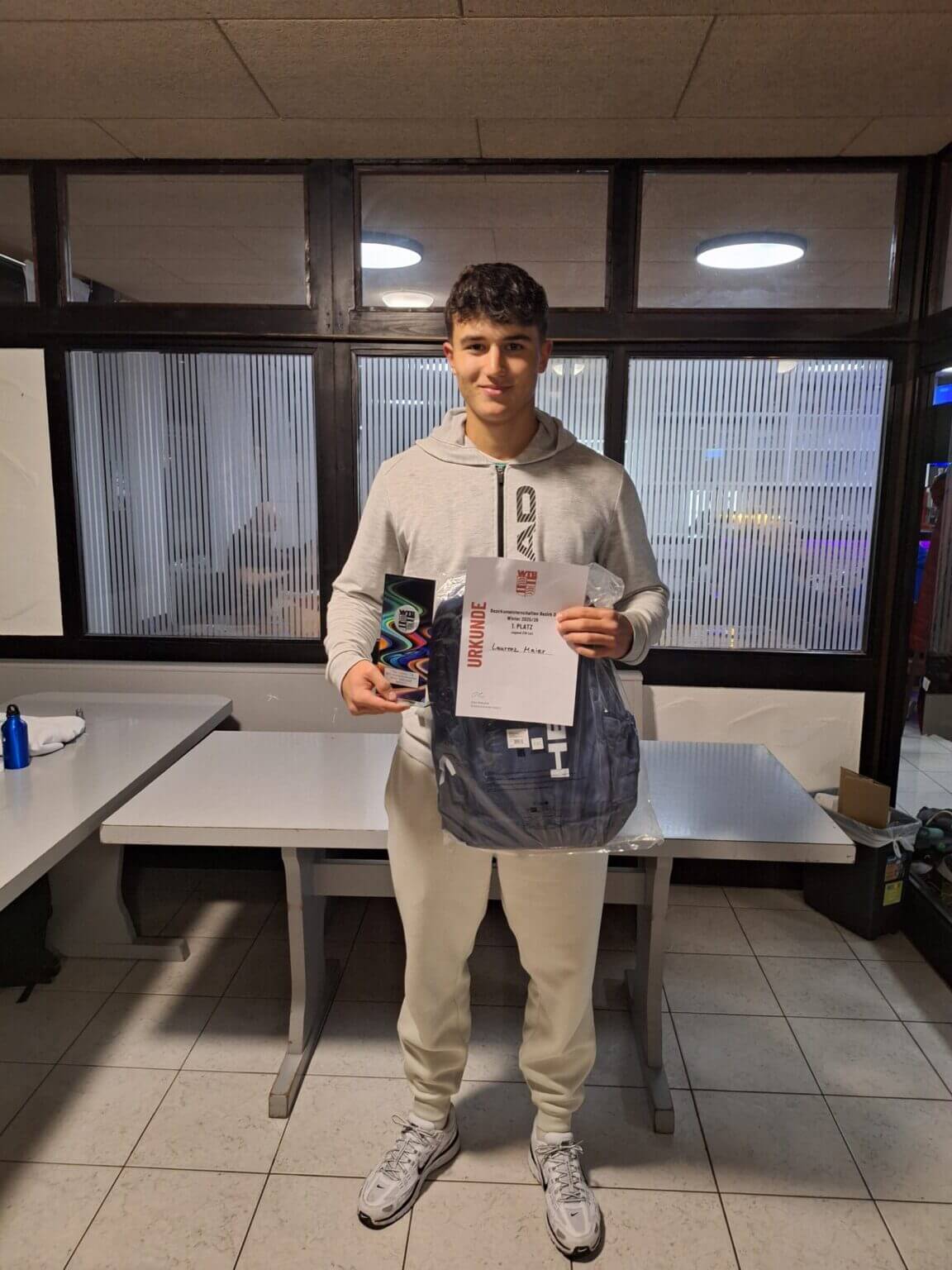 Junger Mann hält Urkunde und Pokal bei Preisverleihung